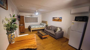 Un espacio habitable compacto con cama, sofá, mesa de comedor y refrigerador.