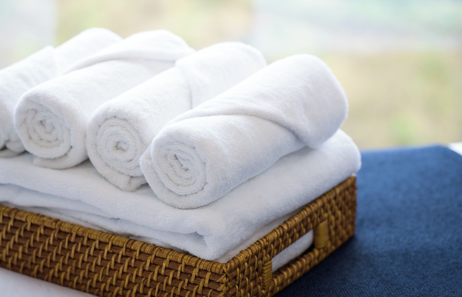 A stack of white towels in a wicker basket.