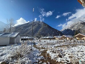 A snowy outdoor area with tents and a mountain in the background. - Ibex Camps (Sangla)