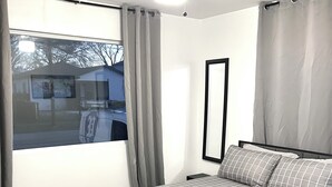 A bedroom with a bed, a ceiling fan, a window with curtains, and a view of the outside. - Compact 3 bed/1bath house 4 miles away from Downtown (Dallas)