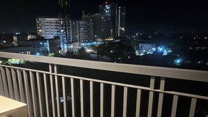 Ein Balkon mit Geländer, der auf eine nächtliche Skyline blickt.
