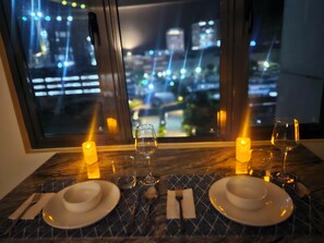 A dining table set for two with candles, plates, and cutlery. - Fabulous view studio suite with terrace in Stitch Style Condotel Iloilo City (Iloilo City)