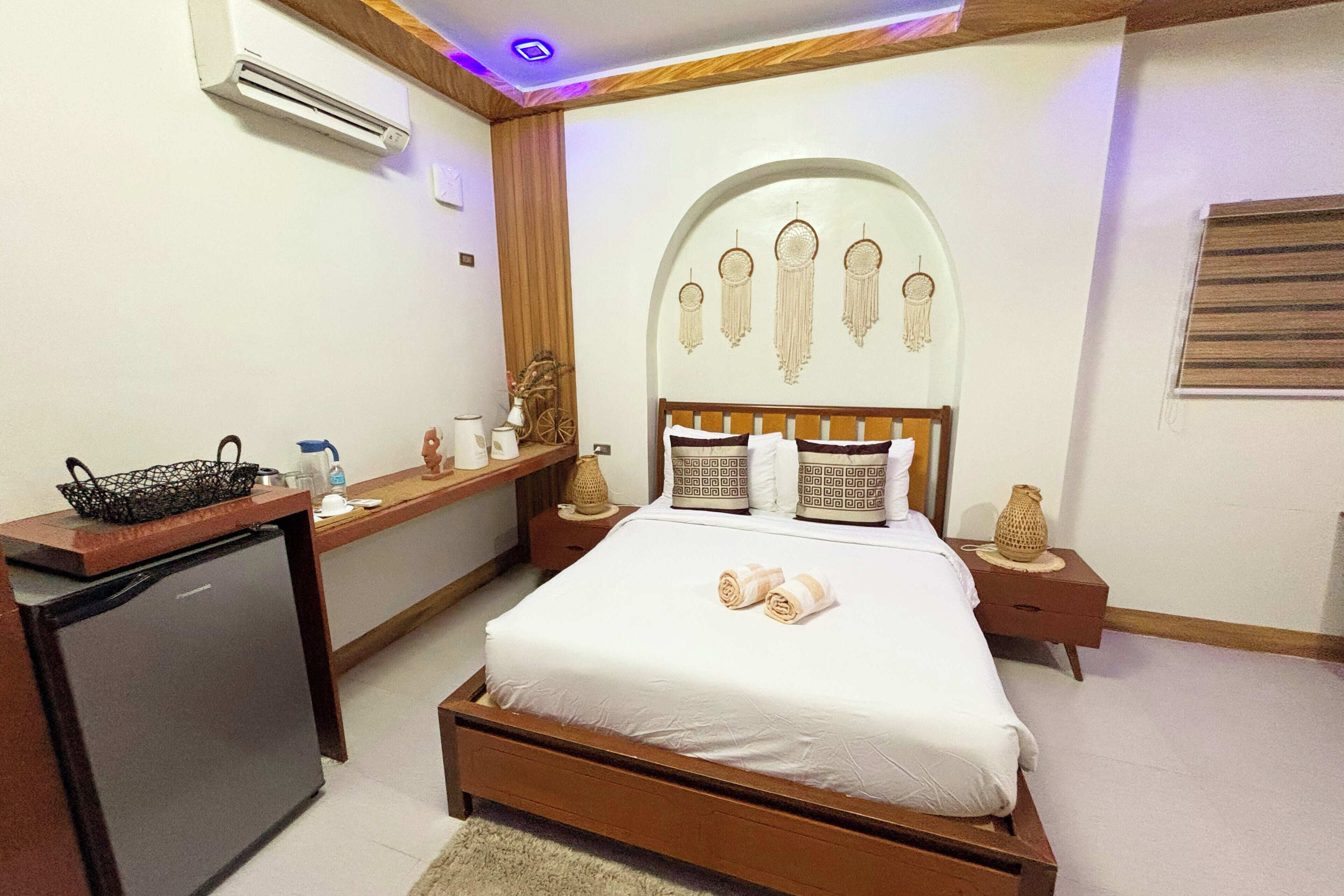 Un dormitorio con cama, escritorio, refrigerador y adornos en la pared.