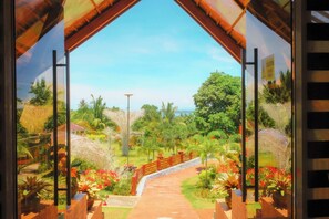 A pathway leading through a lush garden with a wooden bridge, surrounded by greenery and palm trees. - Gamboa's Orchard Malilipot Albay (Bacacay)