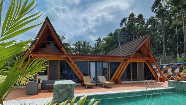Un complexe hôtelier doté d’une piscine, de chalets en bois et d’une végétation tropicale.