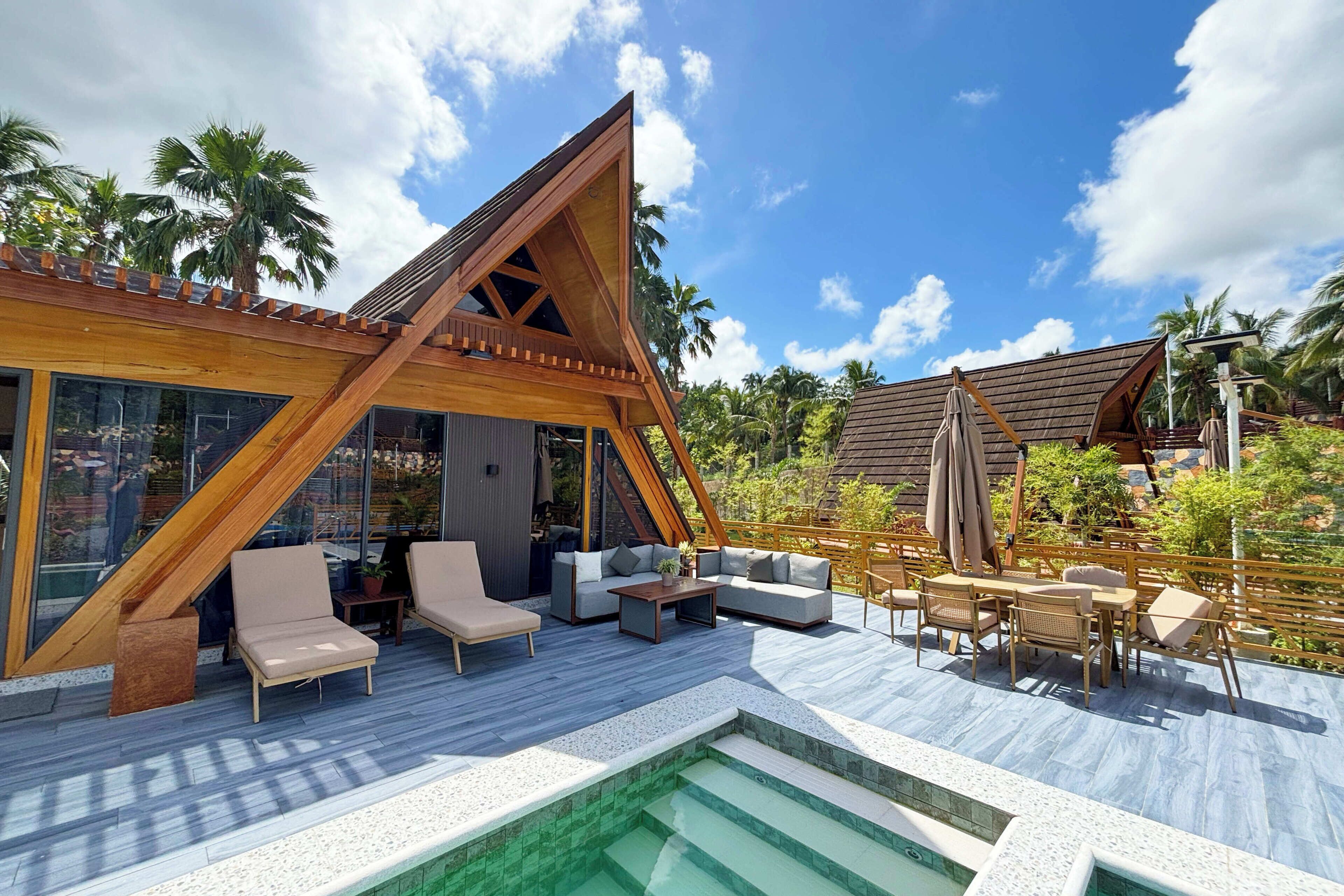 A modern outdoor lounge area with a pool, wooden deck, and seating arrangements.