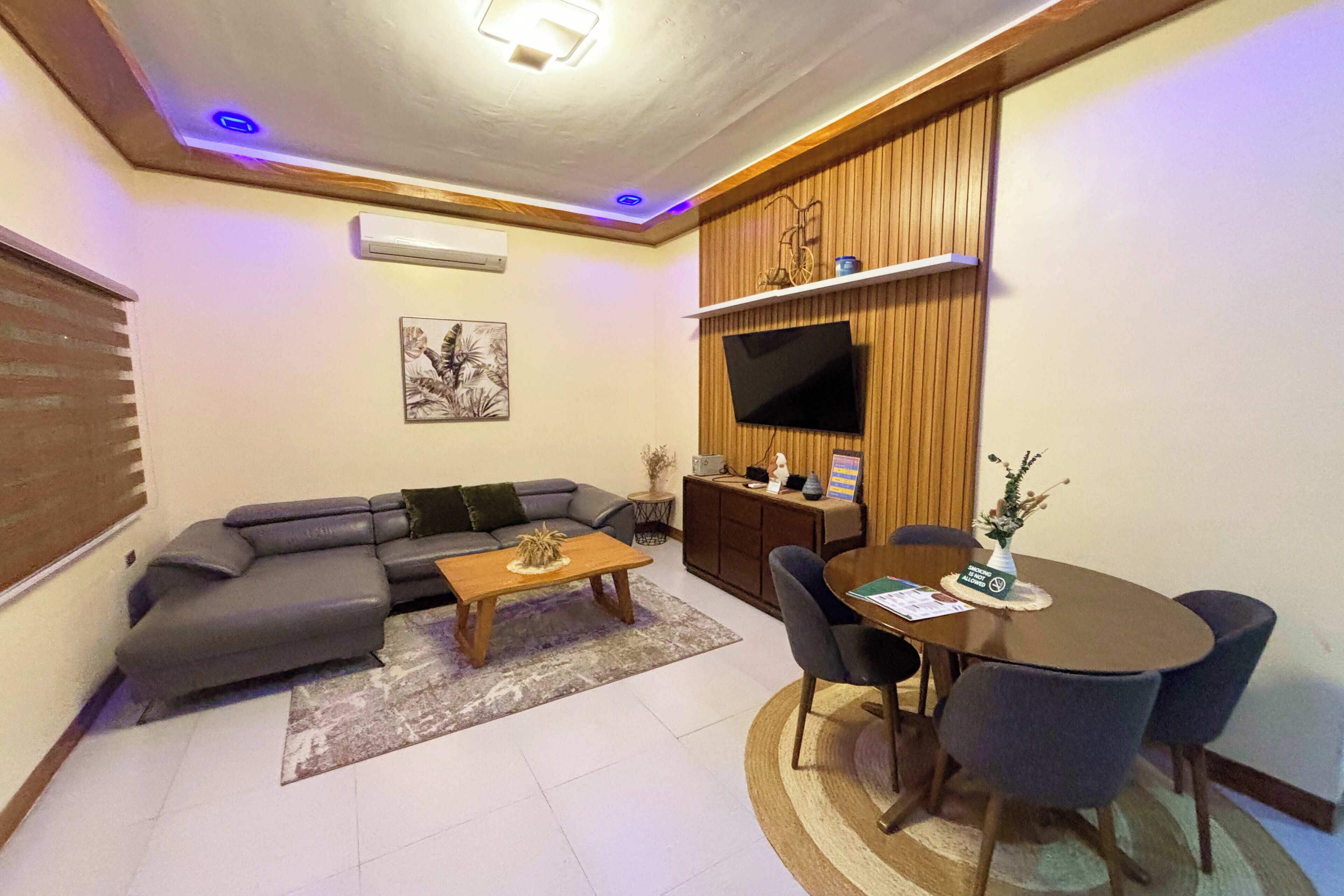 A living room with a sofa, coffee table, TV, and dining area with chairs.