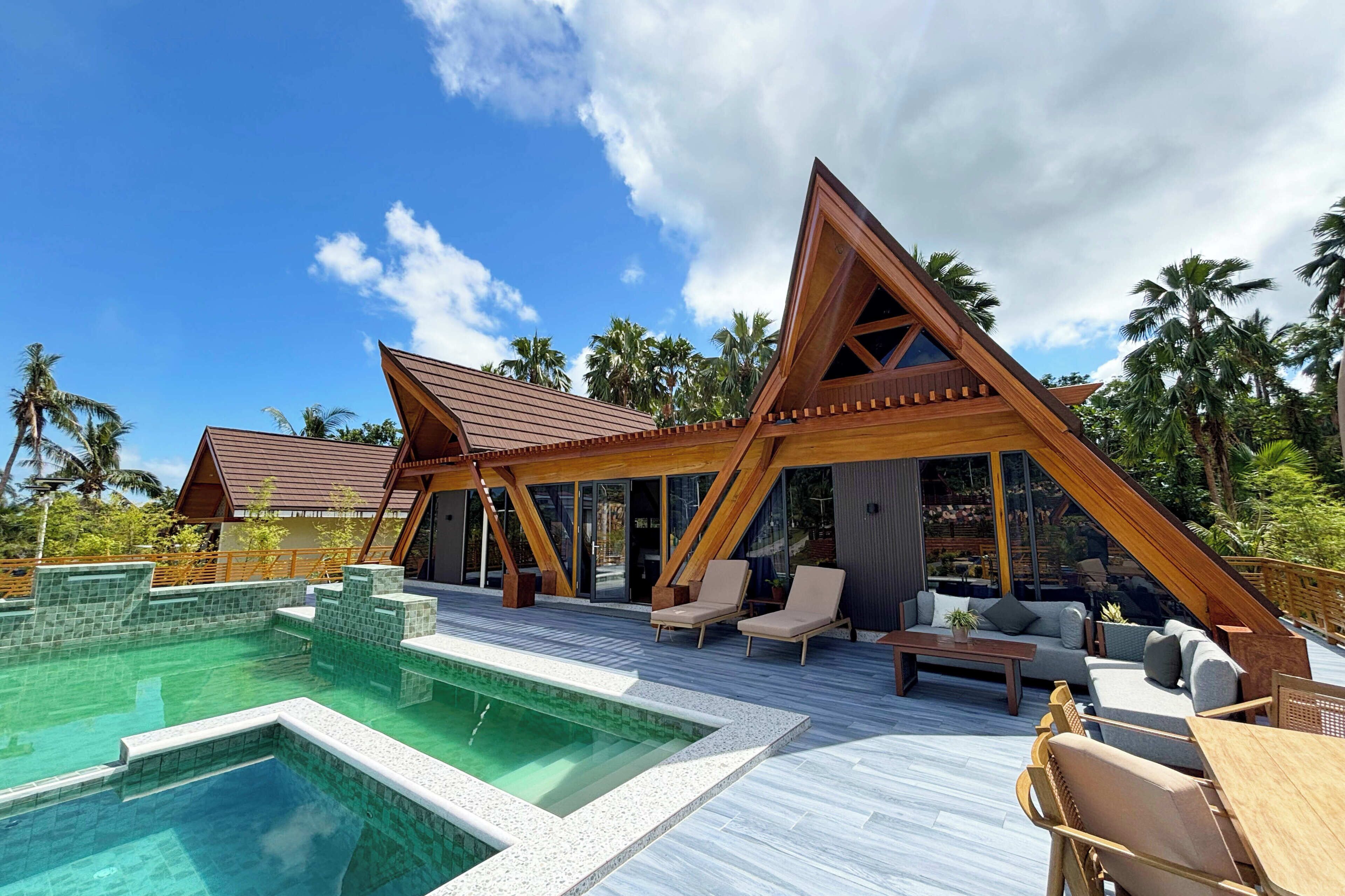 A resort with a swimming pool, lounge area, and wooden architecture.