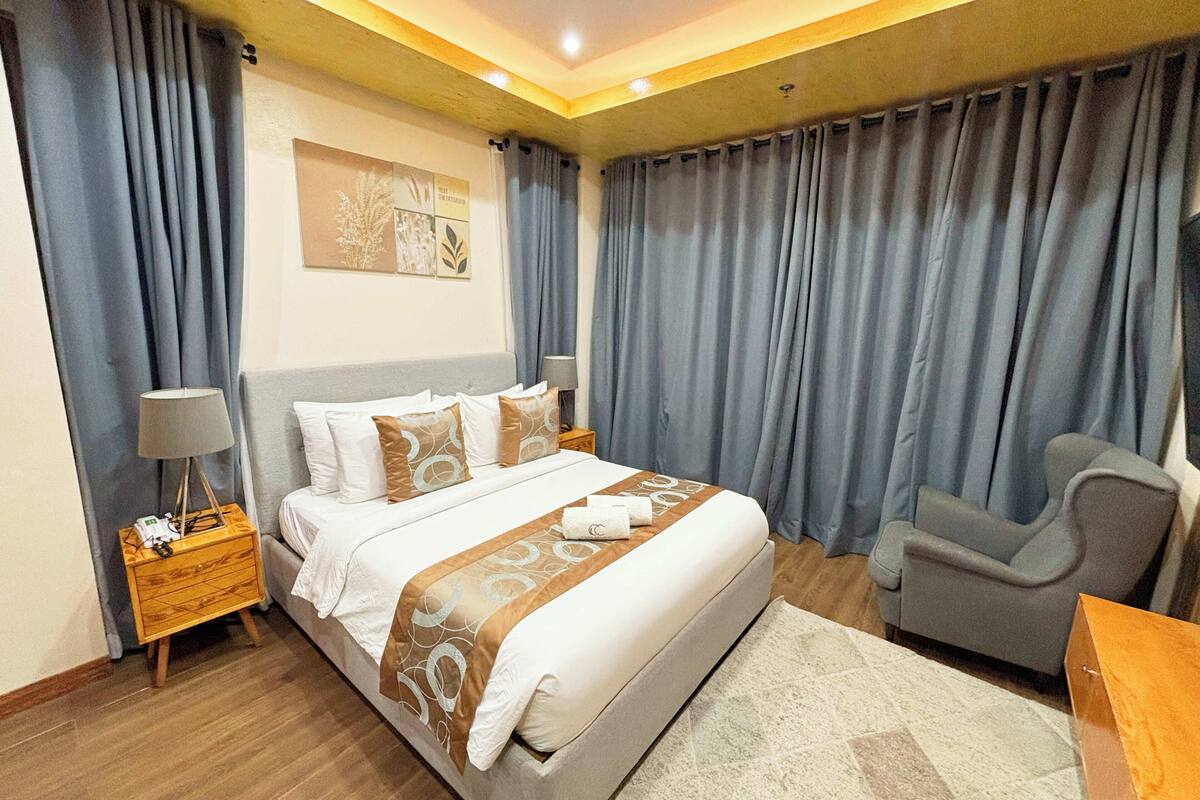 Ein Hotelzimmer mit einem großen Bett, einem Sessel, einem Nachttisch und einer Lampe.
