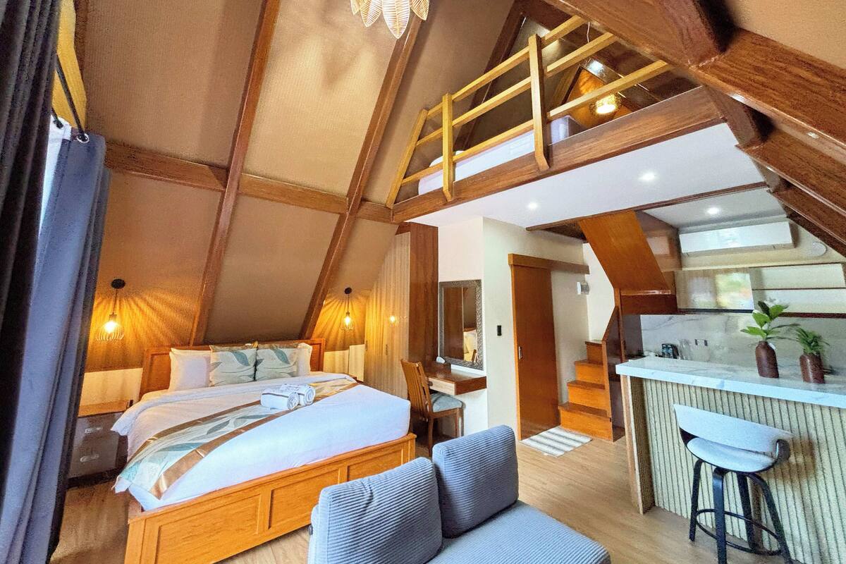 Ein Schlafzimmer mit erhöhtem Schlafbereich, einem Schreibtisch und einer Küchenzeile.