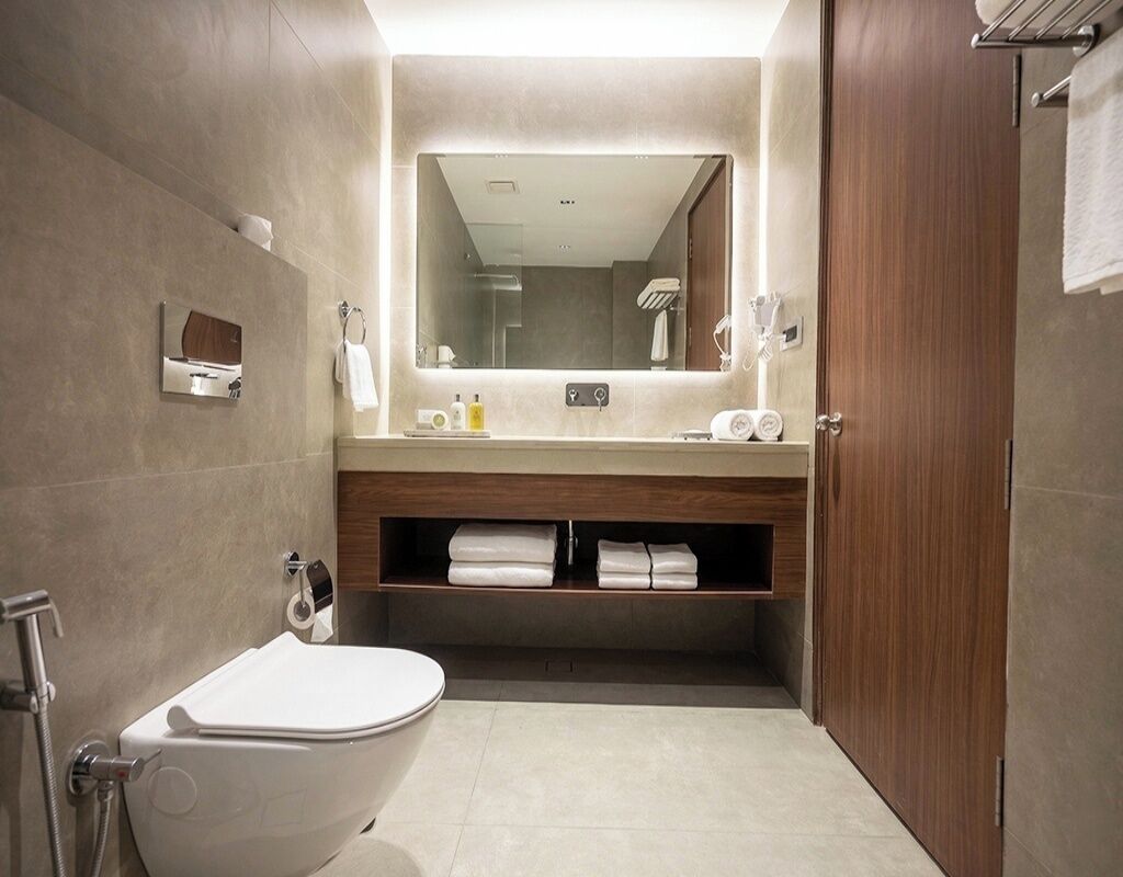 A modern bathroom with a toilet, sink, and mirror.