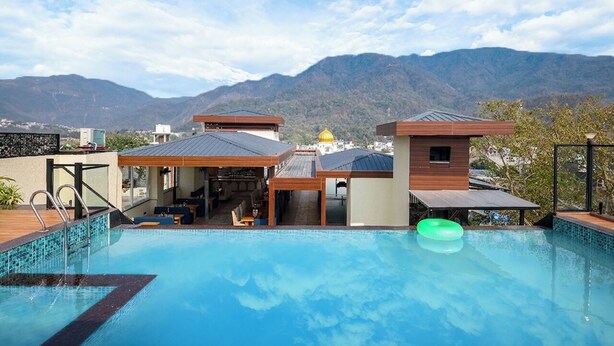 Una piscina sul tetto con vista sulle montagne, un pontile in legno e un'area salotto coperta.