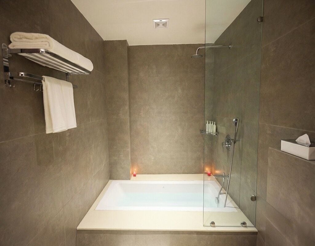 Un baño moderno con ducha de mampara de vidrio, bañera blanca y toallero.