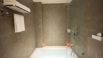 Un baño moderno con ducha de mampara de vidrio, bañera blanca y toallero.