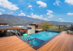 A rooftop pool with a wooden deck, a small building, and a mountain view. - Saltstayz Autograph - Rishikesh Near Triveni Ghat (Rishikesh)
