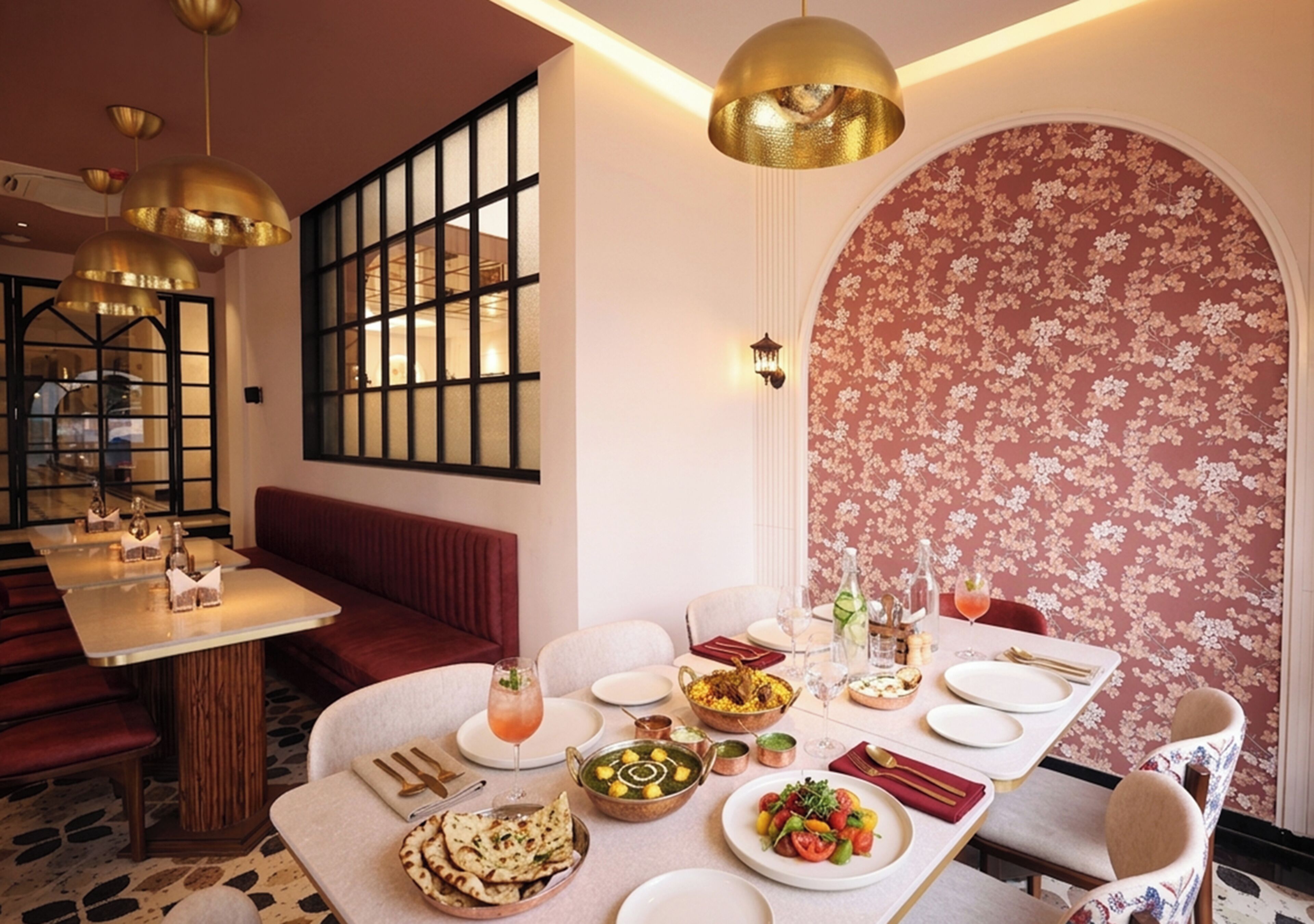 A dining area with a long table set for a meal, a sofa, and a decorative wall with a floral pattern.