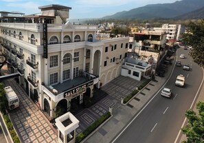 A hotel with a prominent sign, a parking lot, and a road with vehicles. - Saltstayz Autograph - Rishikesh Near Triveni Ghat (Rishikesh)