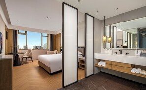 A modern hotel room with a large bed, a desk, and a bathroom with a large mirror and vanity. - Mehood Lestie Hotel (Foshan)