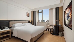 Een moderne hotelkamer met een groot bed, nachtkastje en een bureau met stoel.