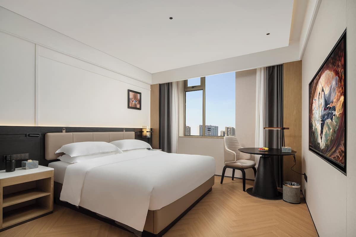Una habitación de hotel moderna con una cama grande, una mesita de noche y un escritorio con una silla.