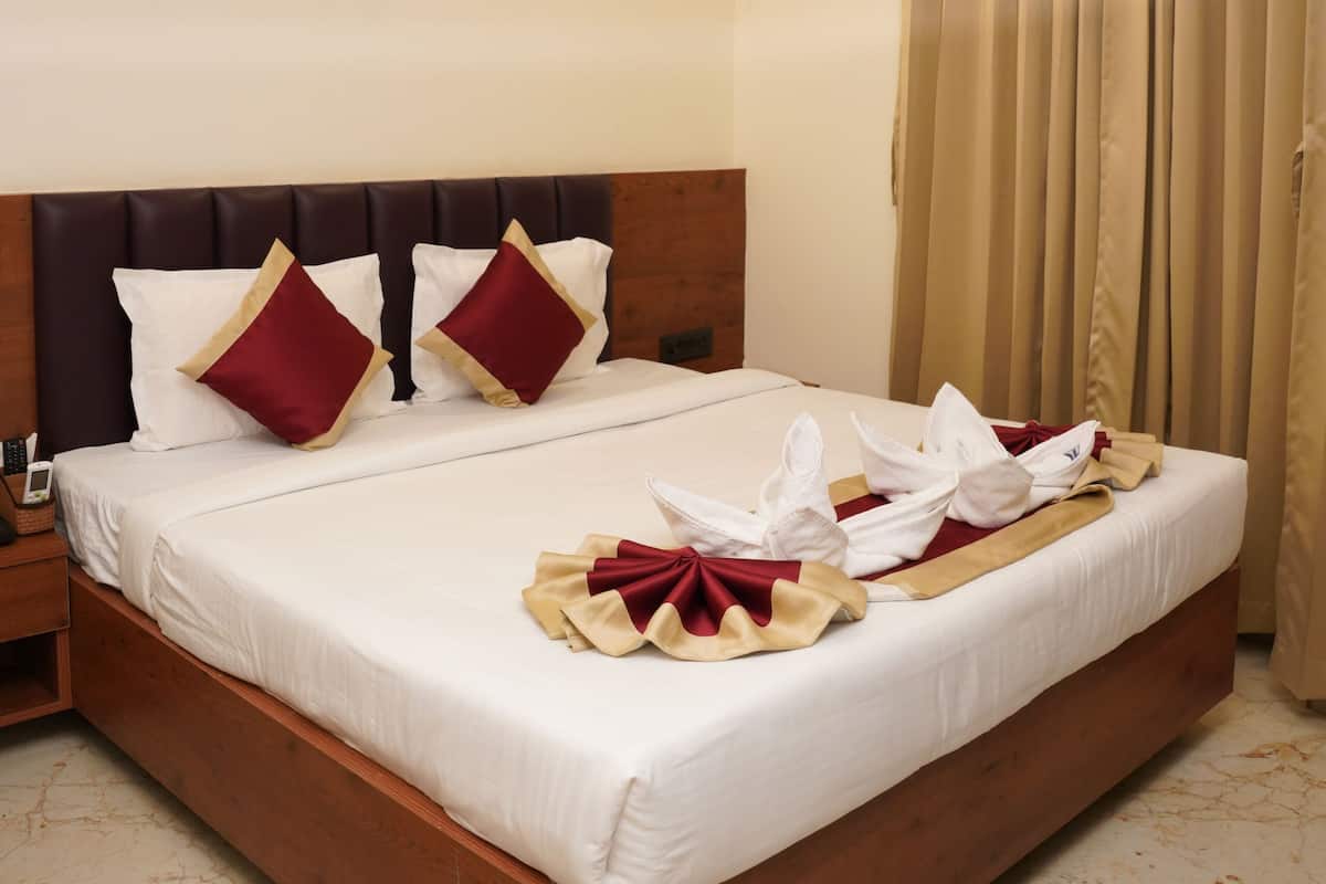 A hotel room with a bed, a ceiling fan, a nightstand, and a window with curtains.