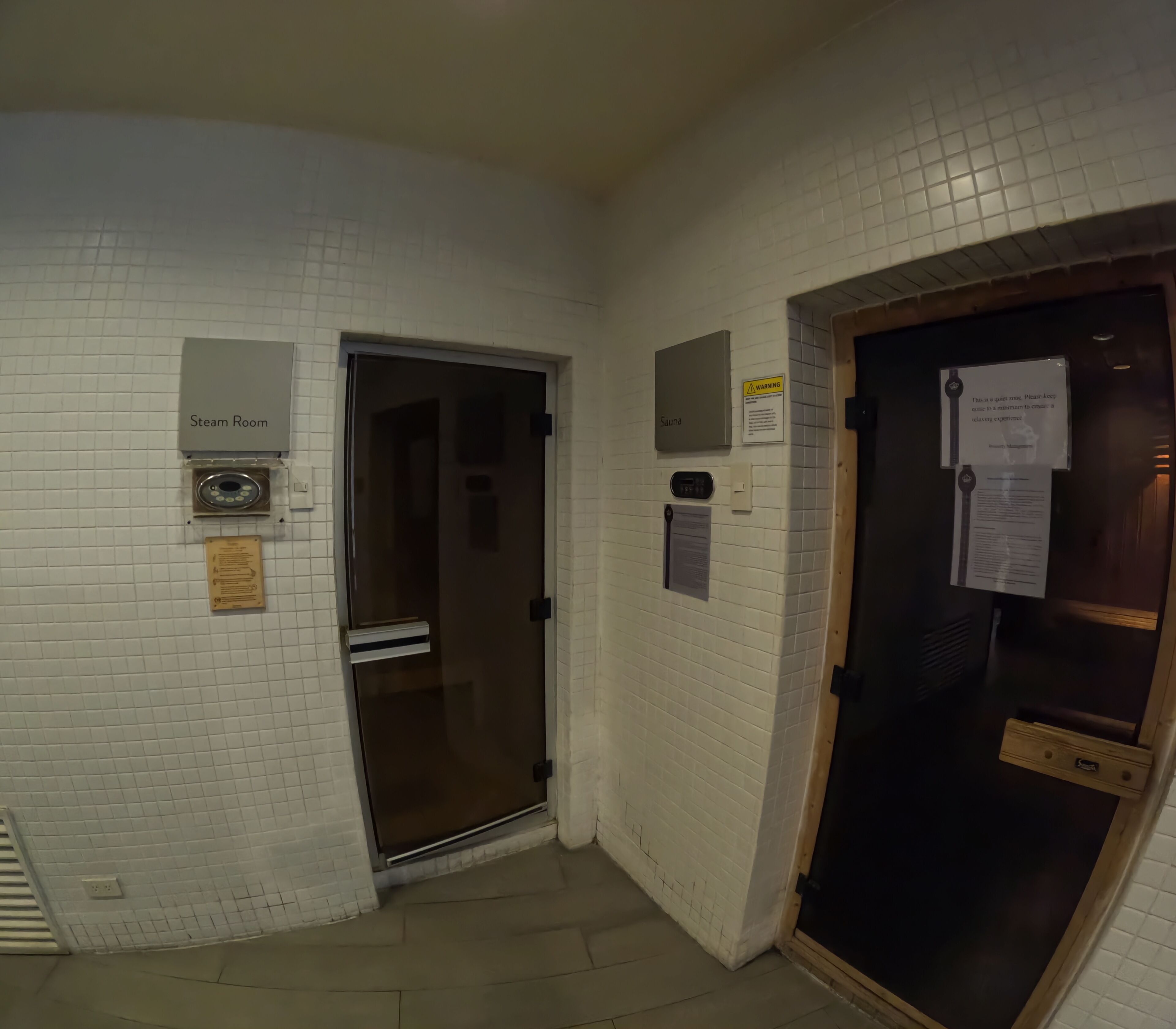 Ein Gang mit Schildern für Dampfbad, Sauna und einem Warnschild an der Wand.