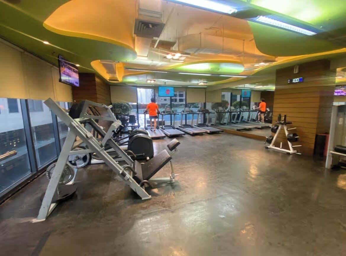 A gym with exercise equipment, a television, and a wooden wall.