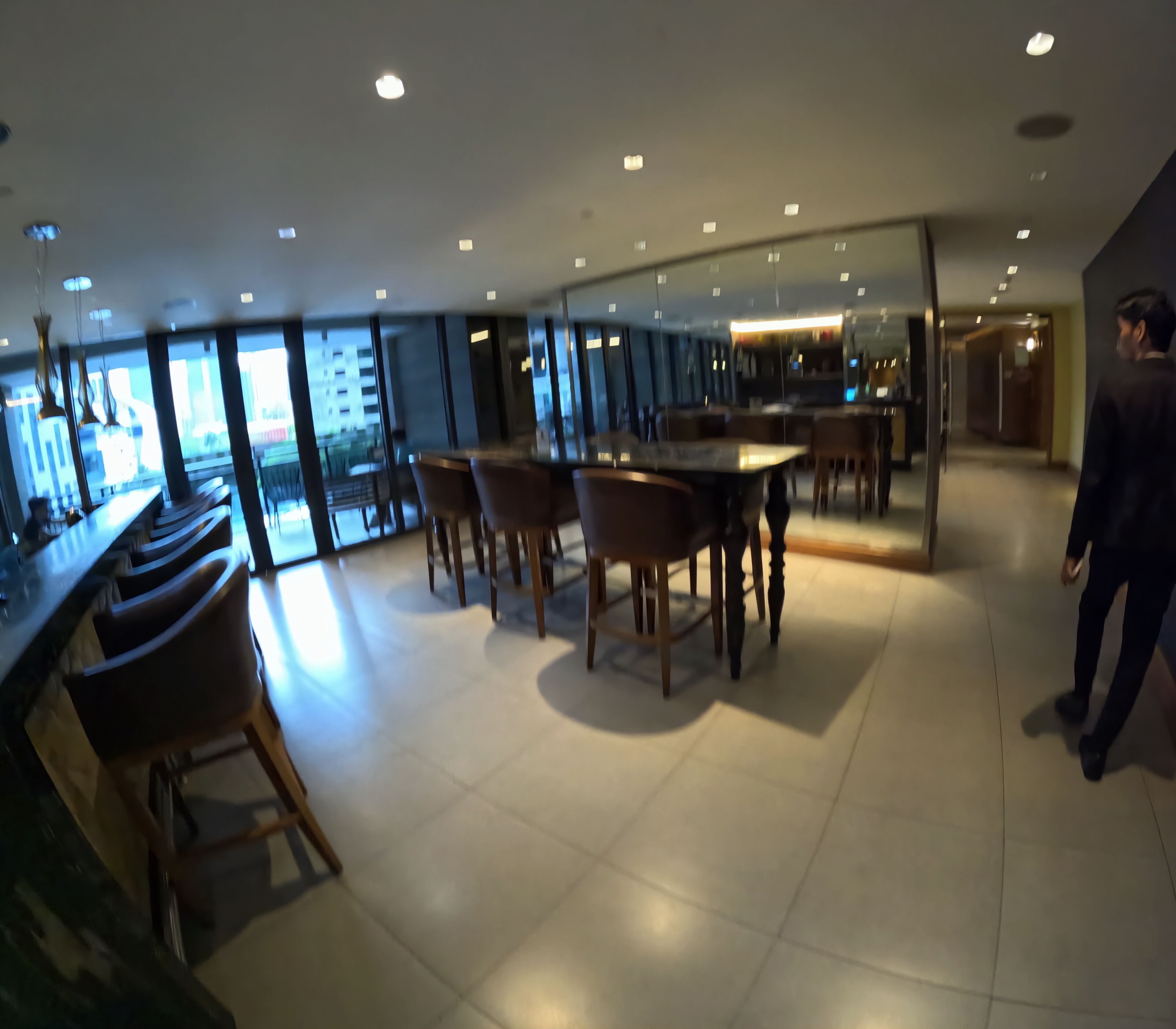 A modern interior with a bar area, seating, and a view through large windows.