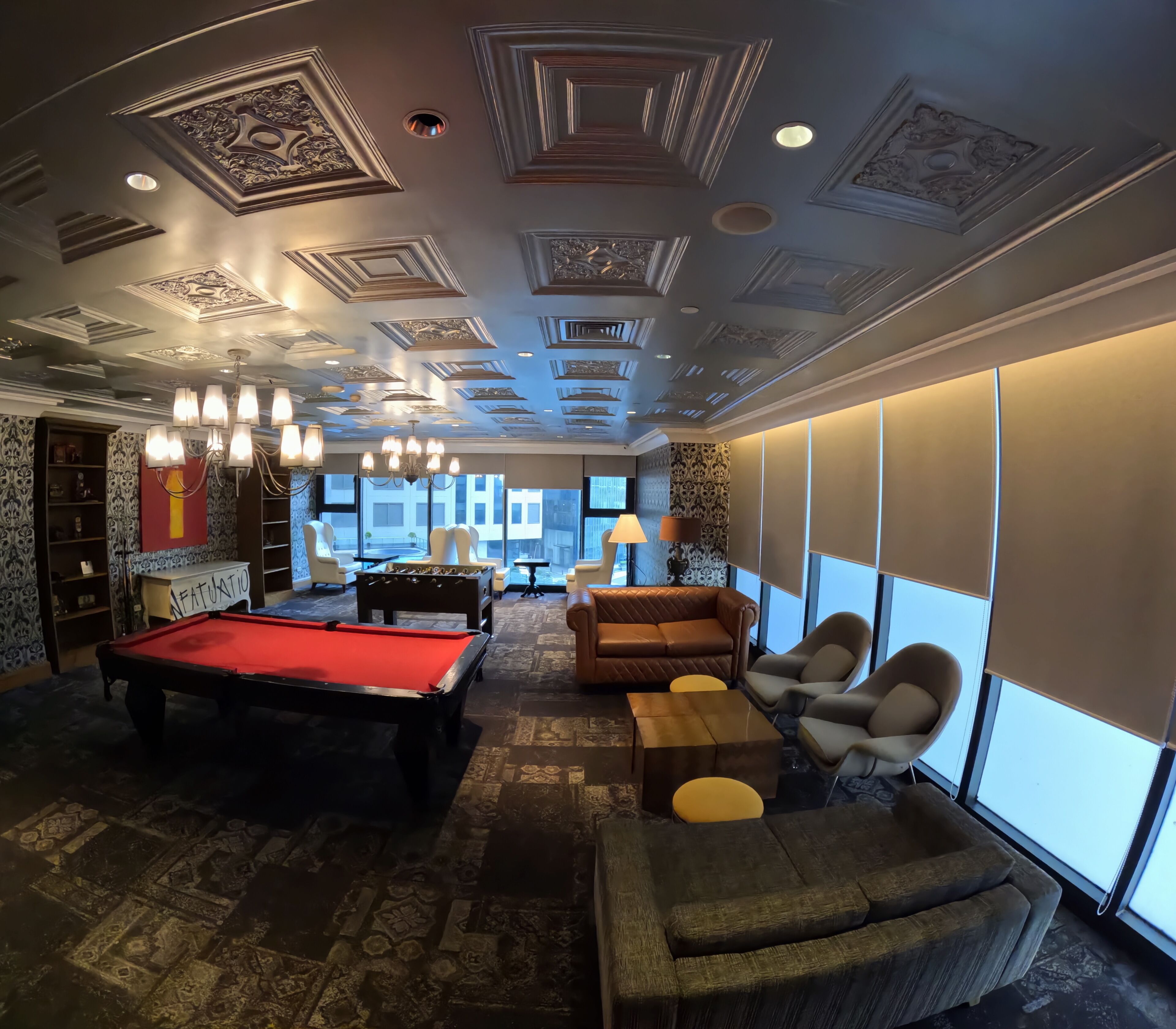 A room with a pool table, leather sofas, and a chandelier.