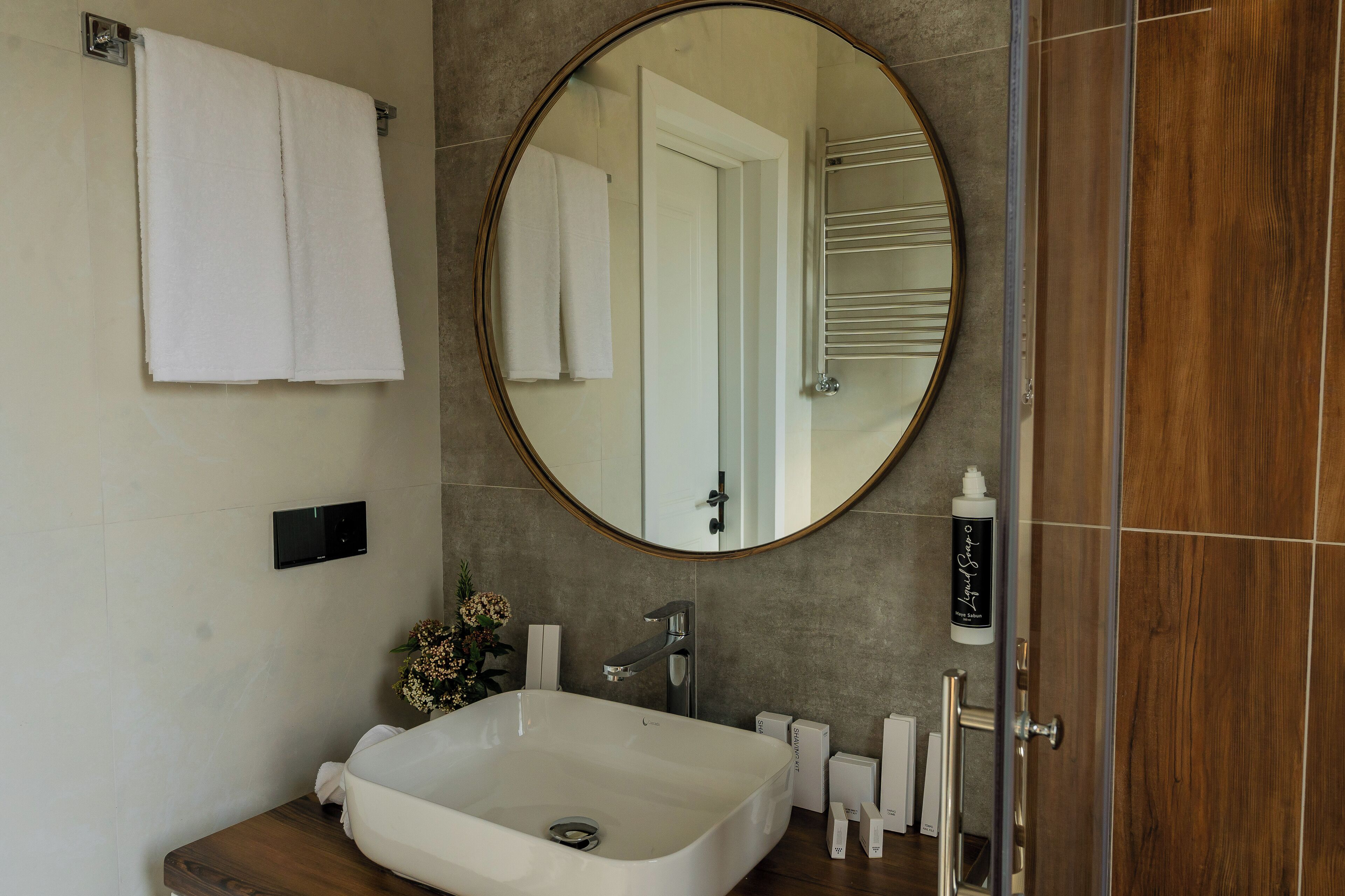 A modern bathroom with a freestanding bathtub, a round mirror, and a towel rack.