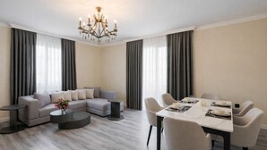 Un salon moderne avec un canapé gris, une table basse ronde et un coin repas comprenant une table et des chaises blanches.