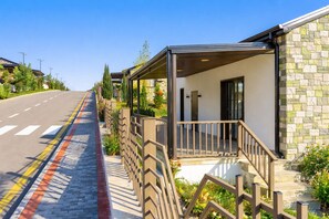 A modern building with a covered porch, a stone facade, and a clear road with zebra crossings. - Sugovushan Hotel and Cottages (Sugovushan)
