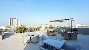 A rooftop patio with outdoor furniture, a pergola, and a view of the cityscape. - ALIVAA boutique DLF Cybercity Gurugram (Gurugram)