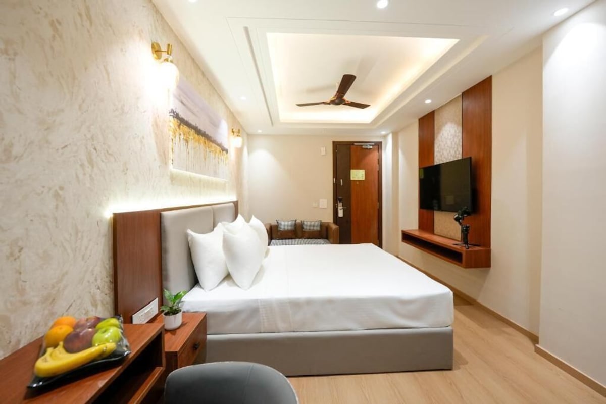 A hotel room with a bed, bedside table, fruit bowl, TV, and ceiling fan.