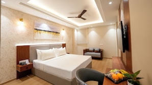 A modern hotel room with a bed, bedside table, desk, chair, and a fruit basket. - ALIVAA boutique DLF Cybercity Gurugram (Gurugram)