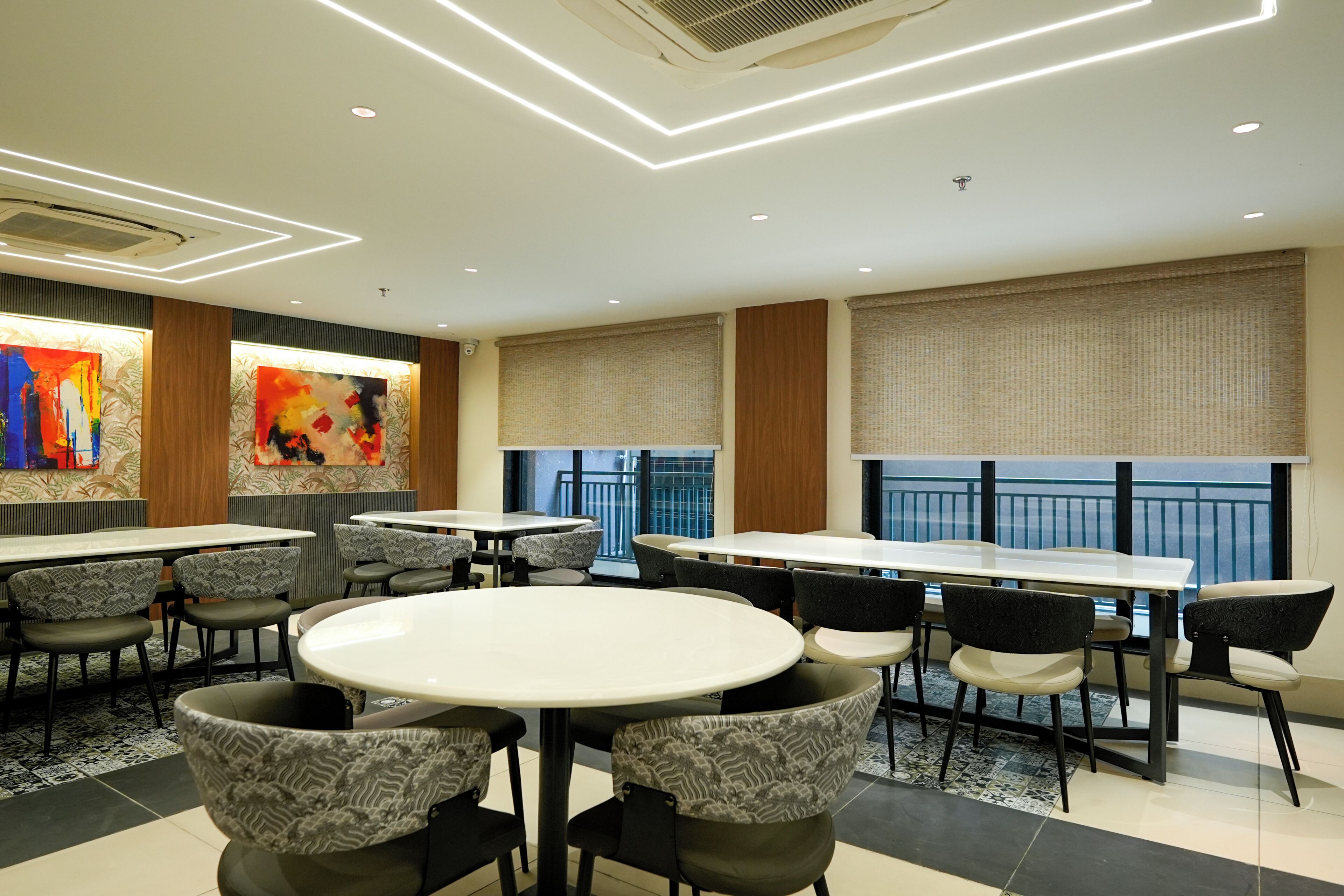 A modern dining area with round tables, patterned chairs, and artwork on the walls.