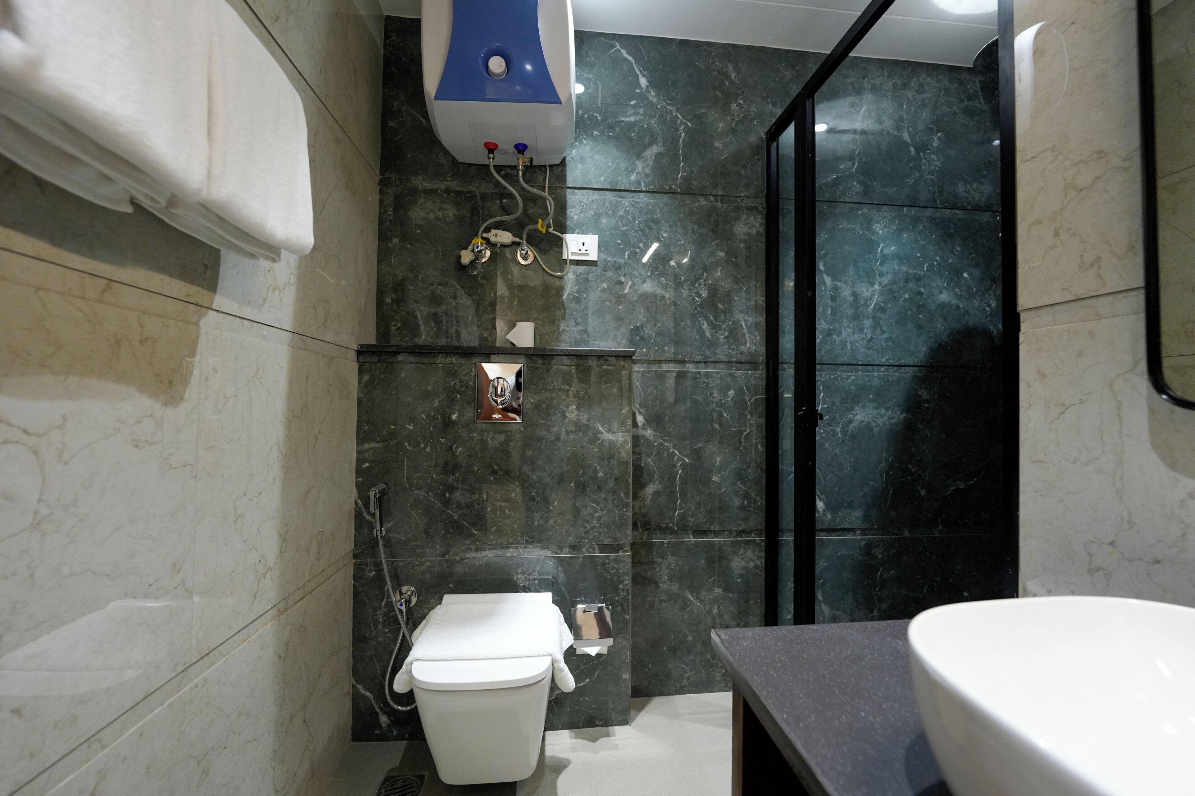 A bathroom with a toilet, a shower, a sink, and a towel dispenser.