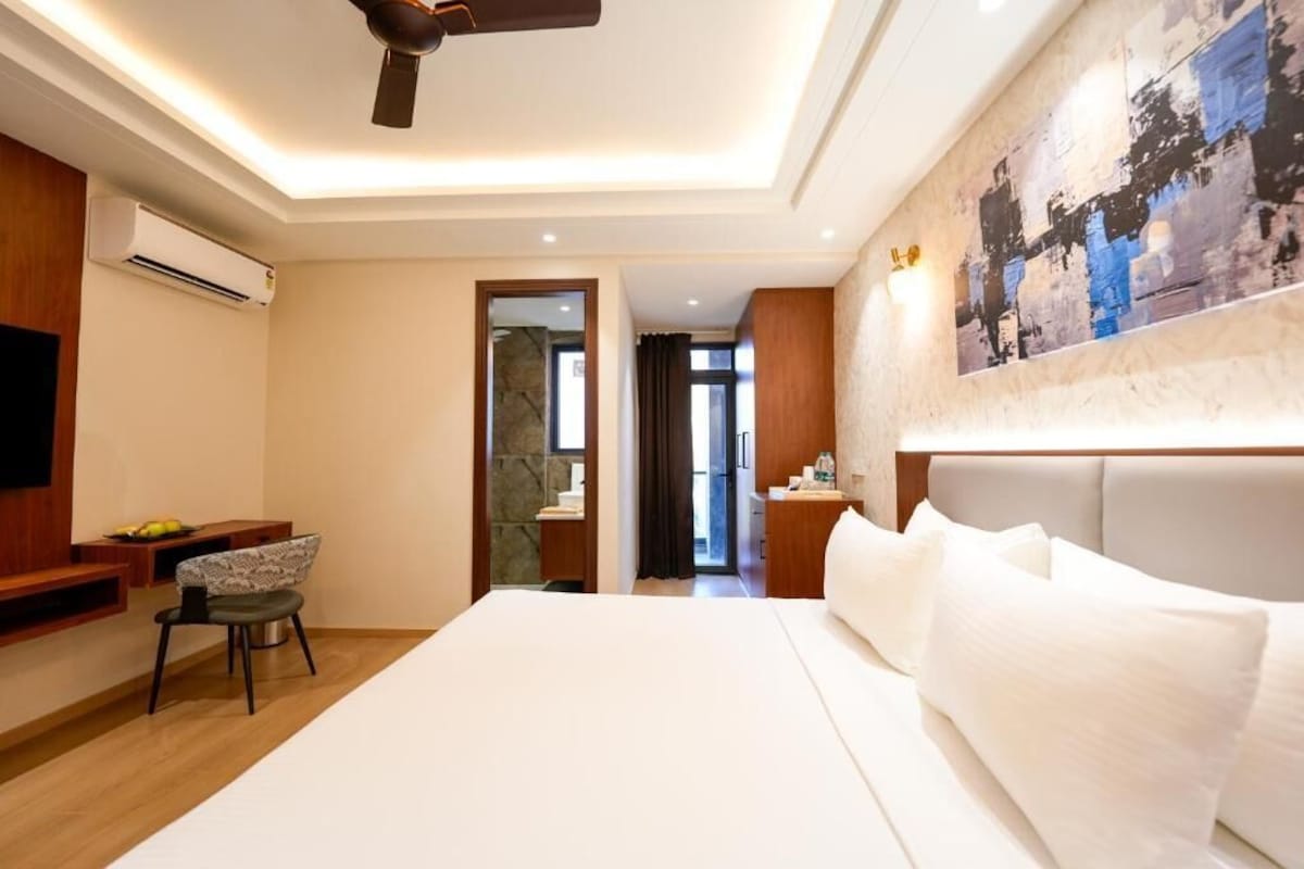 A hotel room with a bed, a desk, a chair, and a television.