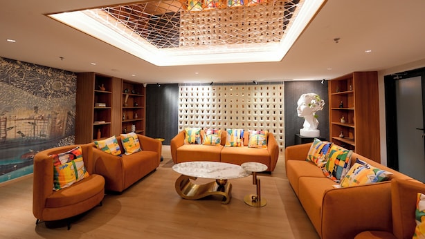 A modern living room with orange sofas, a marble coffee table, and a skylight ceiling. - ALIVAA boutique DLF Cybercity Gurugram (Gurugram)