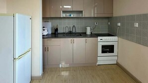 Eine Küche mit Kühlschrank, Herd, Spüle und Schränken.