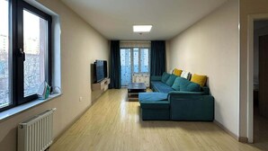 Ein schmaler Flur mit einer Sofaecke, einem Fernseher und einer Heizung.