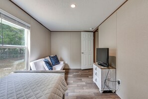 A bedroom with a bed, a TV on a wooden cabinet, a white door, and a window with blinds. - 2 Mi to Ocean! Family-Friendly Emerald Coast Haven (Fort Walton Beach)
