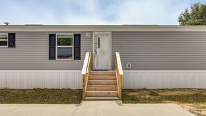 A single-story building with a front door, a wooden staircase, and a concrete driveway. - 2 Mi to Ocean! Family-Friendly Emerald Coast Haven (Fort Walton Beach)