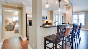 A modern kitchen with a central island, pendant lighting, and a dining area with bar stools. - Condo on Lake Oconee: Big Water Views (Greensboro)