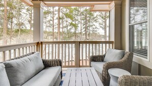 A covered outdoor seating area with wicker furniture and a view of trees. - Condo on Lake Oconee: Big Water Views (Greensboro)