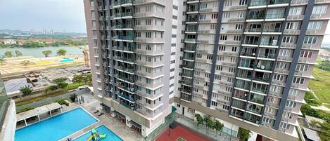 A high-rise residential building with multiple balconies, a swimming pool, and a tennis court.