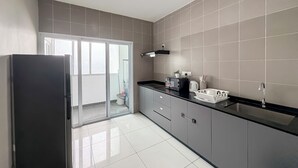 Una cucina moderna con mobili grigi, un piano di lavoro nero e un frigorifero in acciaio inossidabile.
