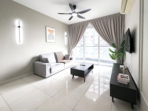 A modern living room with a sofa, coffee table, and TV. - Aurora Residence by Manhattan Group (Puchong)