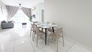 Un'elegante sala da pranzo con un tavolo bianco apparecchiato per quattro persone, circondato da sedie, in una stanza luminosa con un'ampia finestra e una ventola a soffitto.