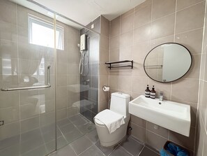 A modern bathroom with a glass-enclosed shower, a white toilet, a sink with a mirror, and a towel rack. - Aurora Residence by Manhattan Group (Puchong)